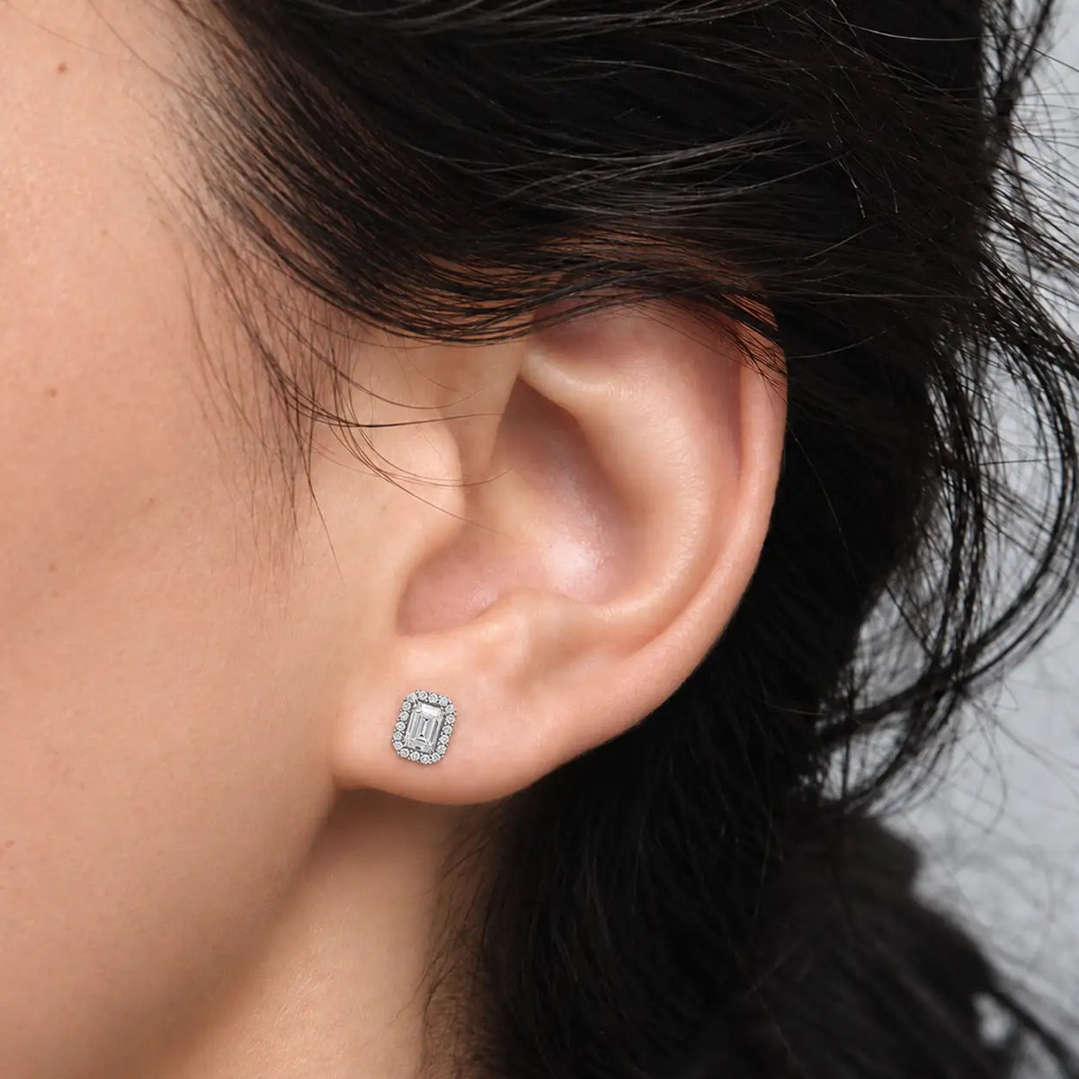 Close-up of luxurious 2ct Emerald-Cut Diamond Halo Stud Earrings worn by a woman