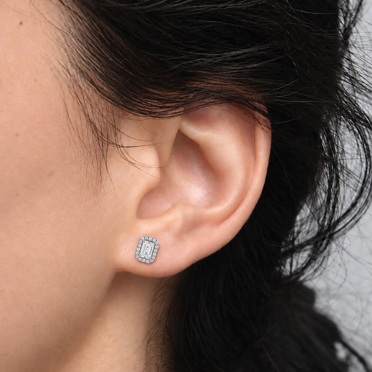Close-up of woman wearing 8ct Bridal Emerald-Cut Halo Diamond Stud Earrings by Fortune Jewellery