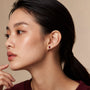 Model wearing yellow gold july birthstone opaque ruby earrings with diamonds