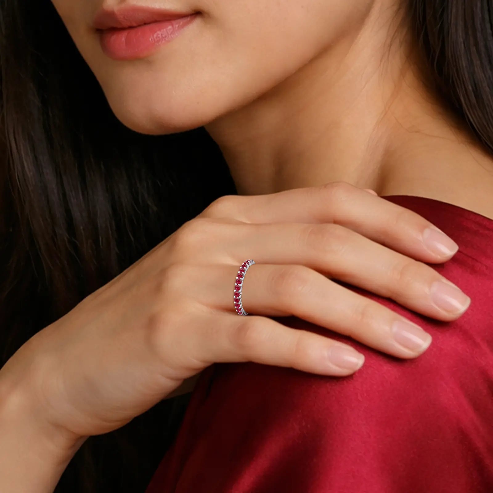 Close-up of a woman's hand wearing a July Birthstone Half Eternity Opaque Ruby Ring